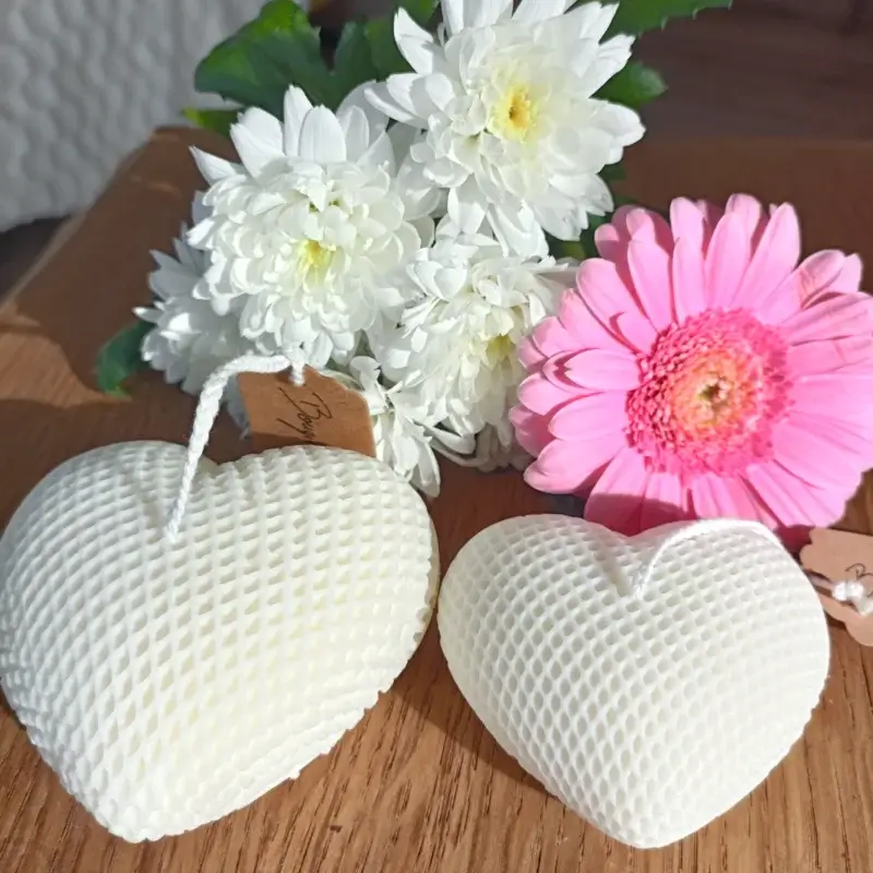 Deux bougies en forme de coeur et dont les motifs sont des nids d'abeille.