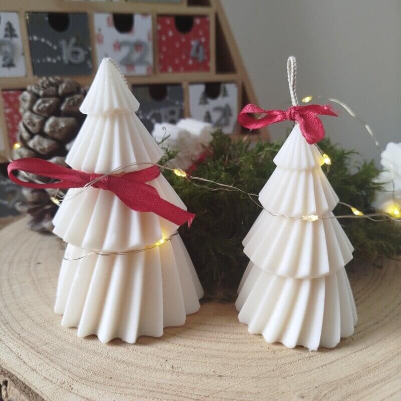 Bougies en forme de sapin de Noël arboré d'un petit de soie rouge.