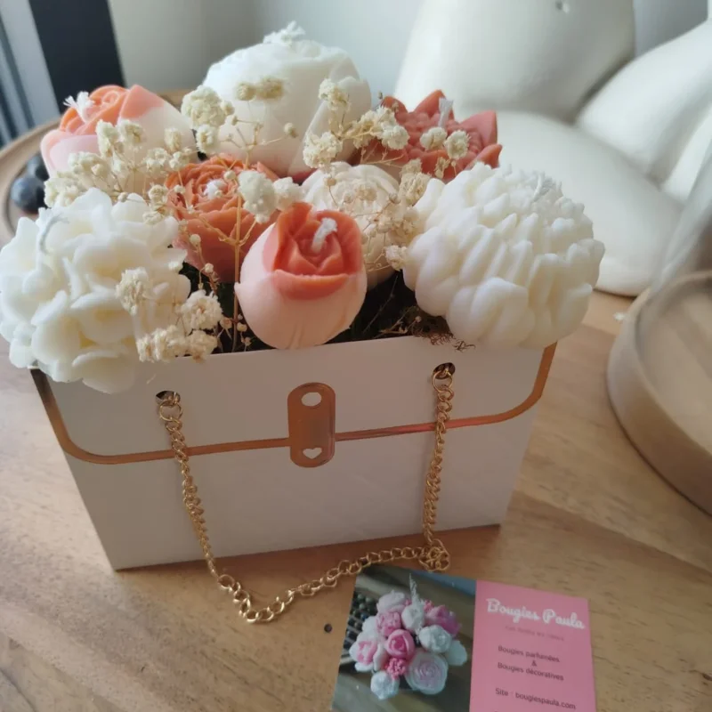 Bouquet de bougies en forme de fleurs de couleurs terracotta et naturel dan un sac blanc ornée d'une chaînette dorée.