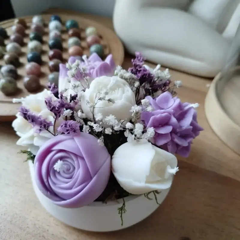 Création artisanale de bougies décoratives dans les tons parme et blanc.